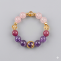 Beaded bracelet with pink, purple, and gold beads on a light gray background