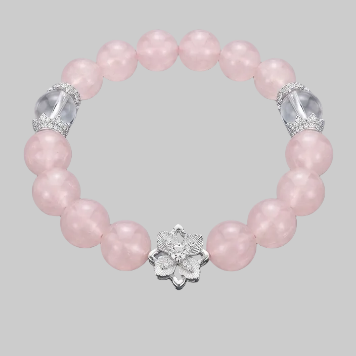 Pink beaded bracelet with silver flower clasp on a gray background