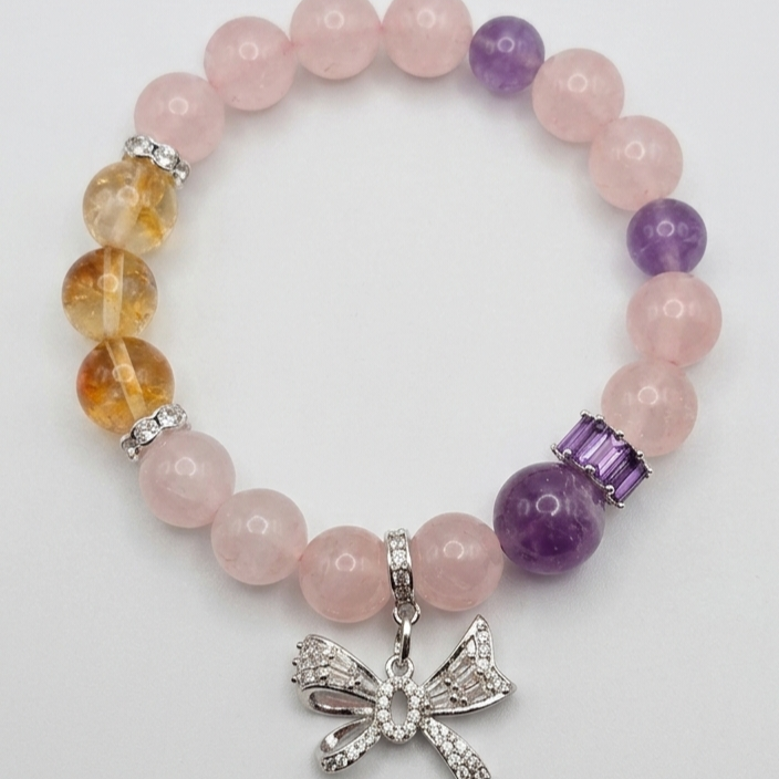 Beaded bracelet with pink, purple, and orange beads and a silver bow charm on a white background