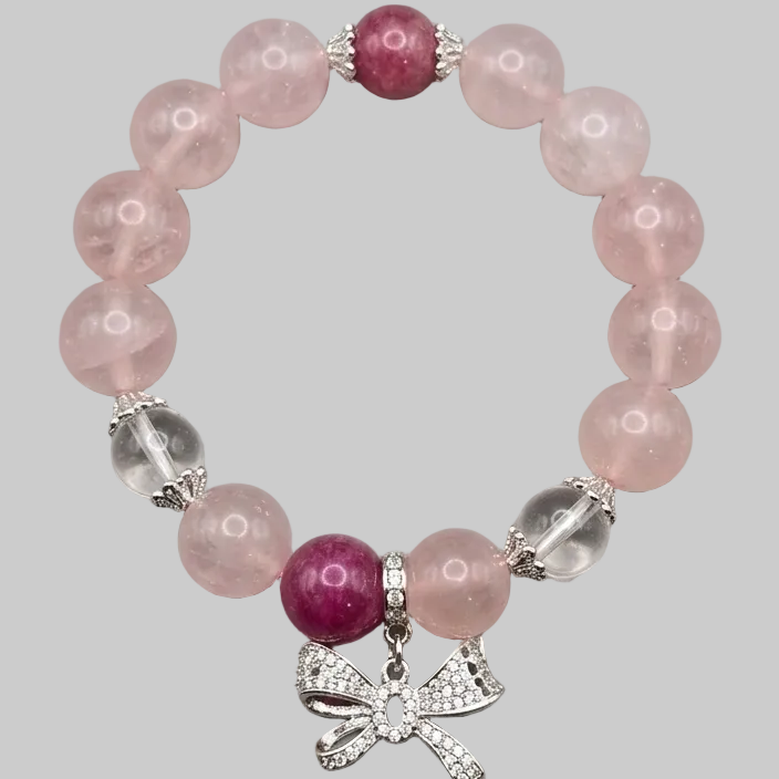 Bracelet with pink and purple beads and a silver bow charm on a gray background