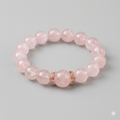 Pink beaded bracelet with a gold accent on a gray background