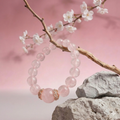 Pink beaded bracelet on a branch with cherry blossoms and rocks