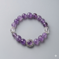 Purple beaded bracelet with a silver clasp on a light gray background