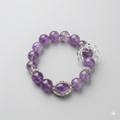 Purple beaded bracelet with silver accents on a light gray background