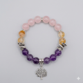 Multicolored beaded bracelet with a silver tree charm on a gray background